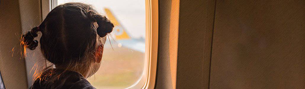 A young girl travels alone by plane to visit a parent